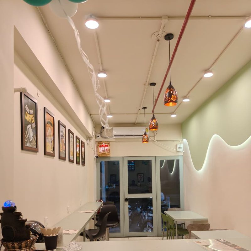 Inside the Twing Cafe Rajkot outlet: framed posters, pendant lights and a green wall with a wave light