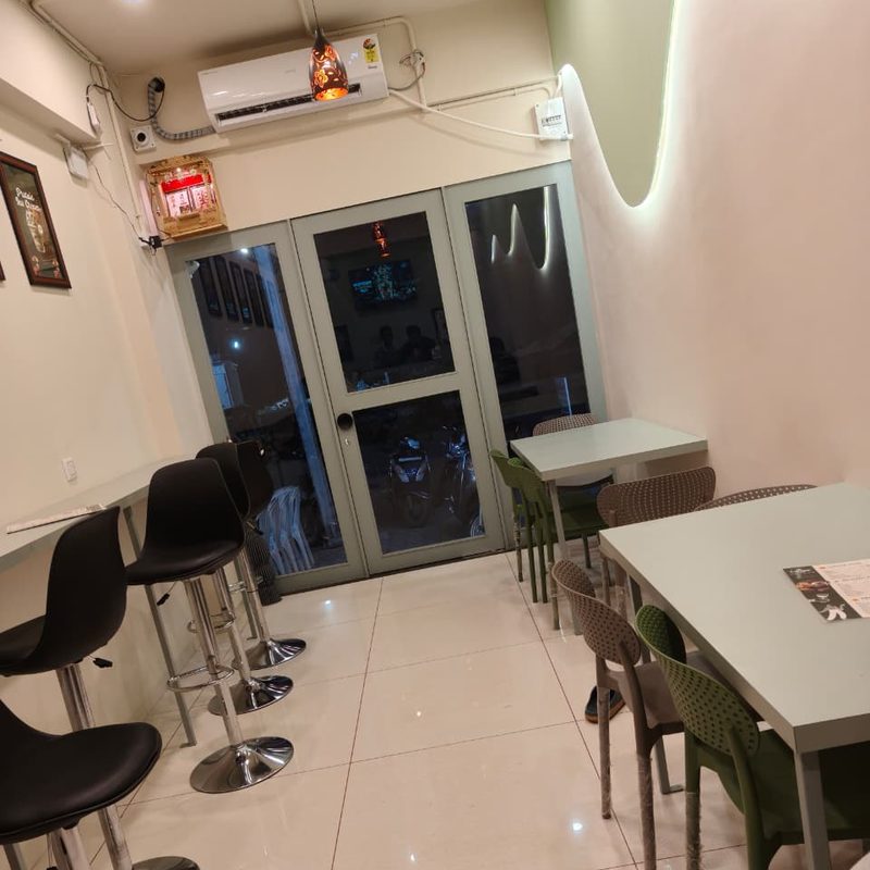 Seating area at Twing Cafe Rajkot with bar stools, tables and chairs